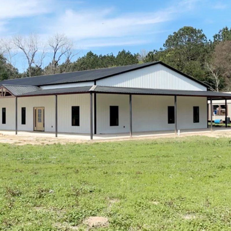 A white building with a black roof and a large porch.